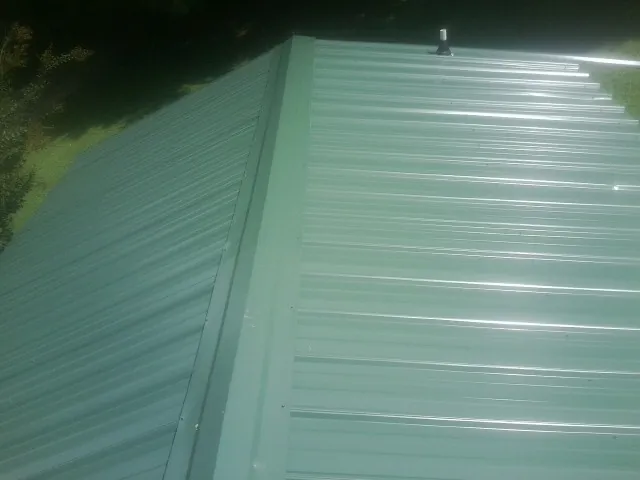 New green metal panels meeting at the ridge of a roof — Flat Roof Repair work by our crew in Andreas