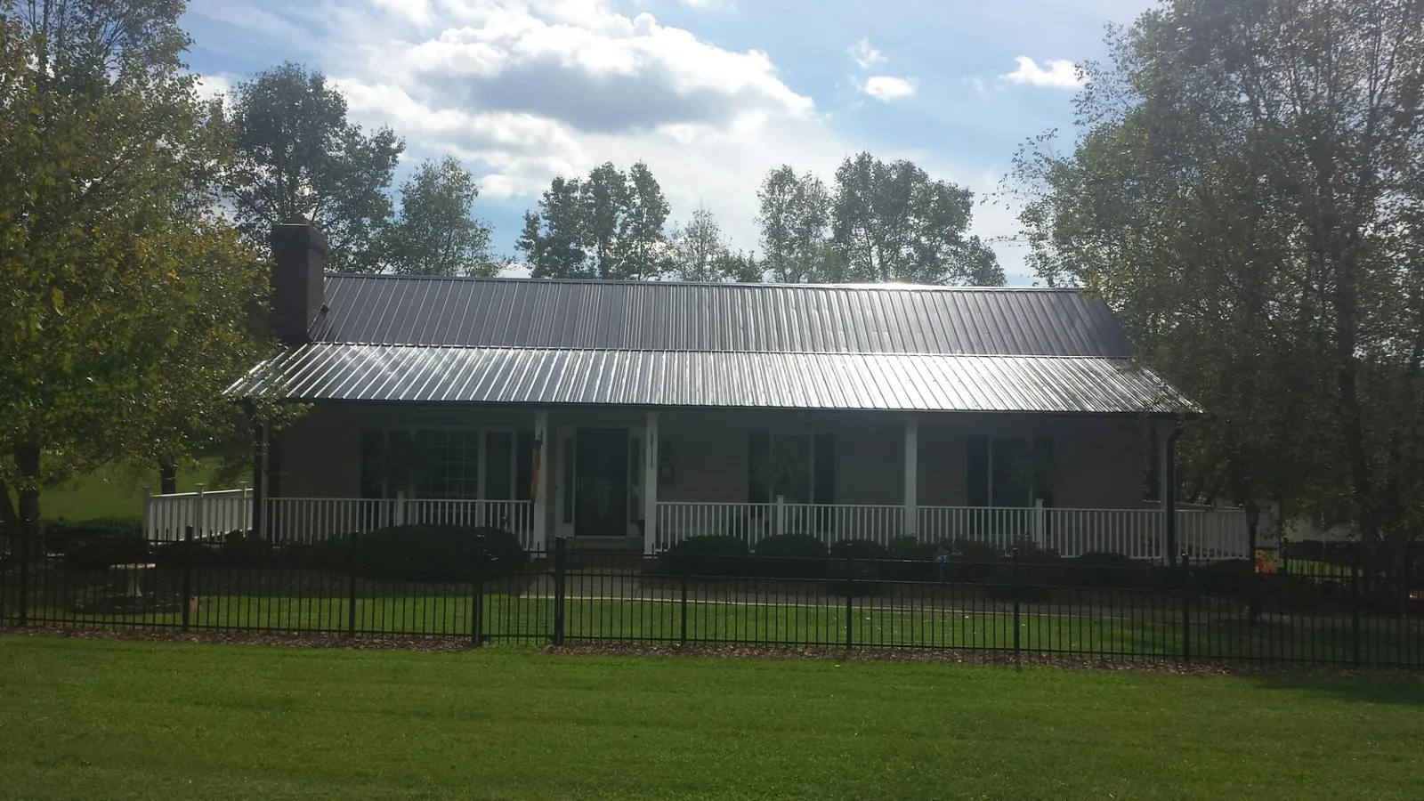 Gray metal roof on a brick ranch with a full width front porch — Gutter Guard Installation work by our crew in Andreas