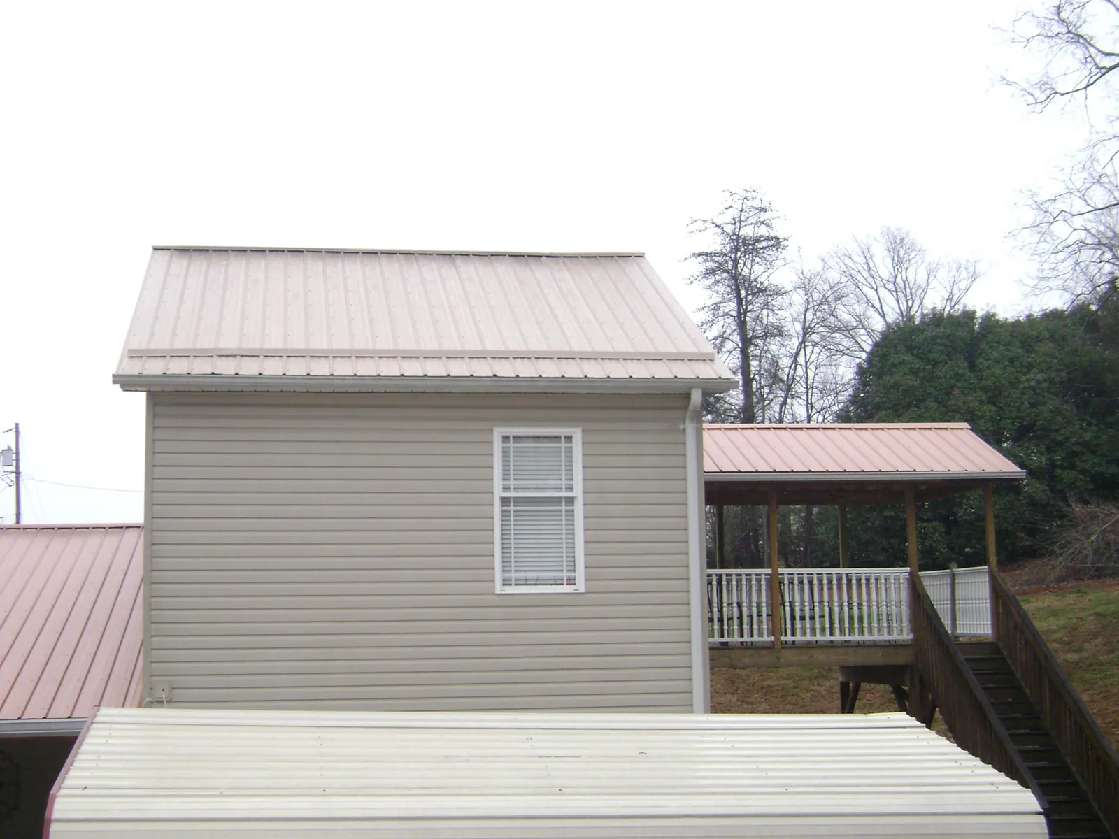 Tan metal roofs on a two story addition and attached porch, from a Roof Replacement job in Andreas